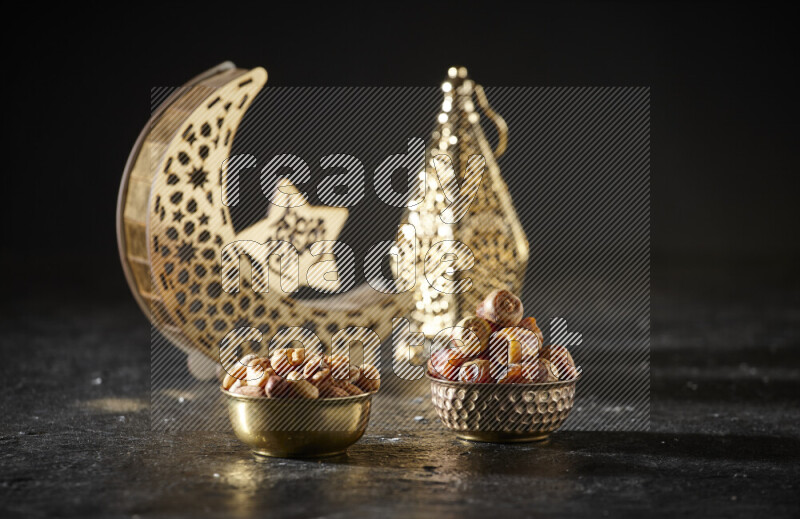 Dates in a metal bowl with mixed nuts beside golden lanterns in a dark setup