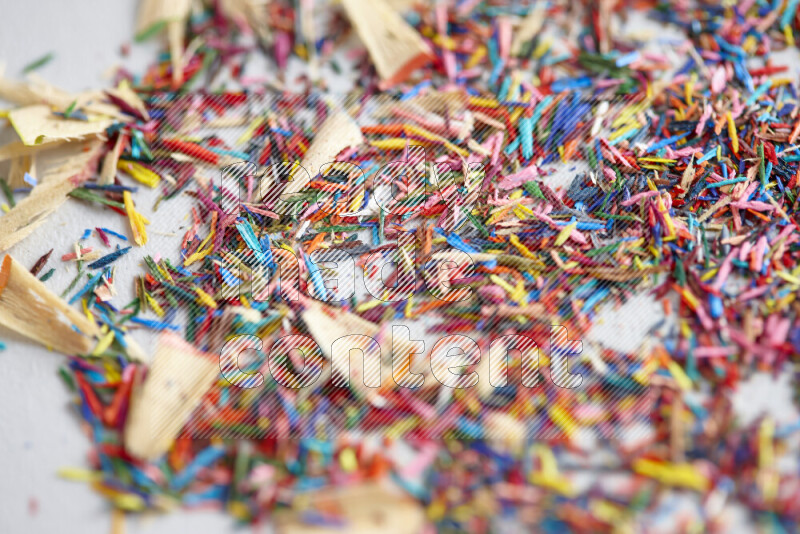 This image showcases a vibrant multicolored pencil shavings scattered on grey background