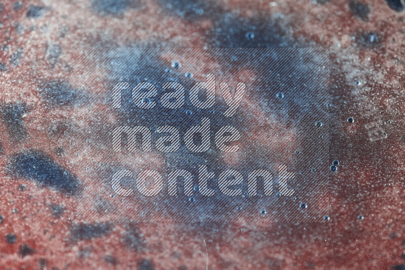 لقطات مقربة لقطرات ألوان مائية زرقاء على سطح الزيت على خلفية حمراء