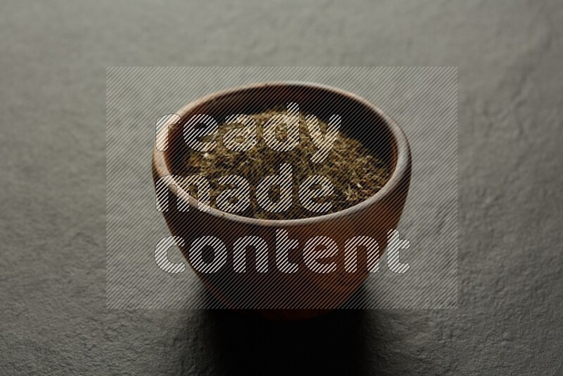 wooden round sauce bowl filled with herbs on grey textured countertop