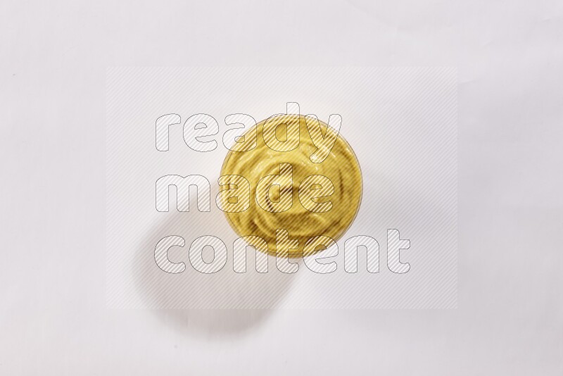 A glass bowl full of mustard paste on a white flooring