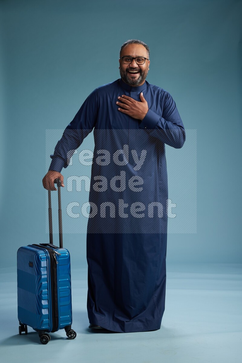Saudi Man without shimag Standing pulling travel bag on blue background