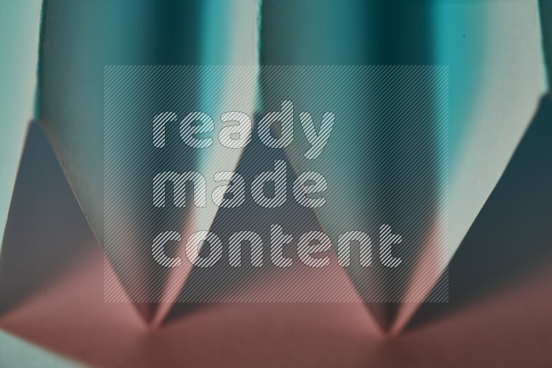 صورة مجردة مقربة تظهر طيات ورقية هندسية حادة بتدرجات اللون الأخضر والأحمر