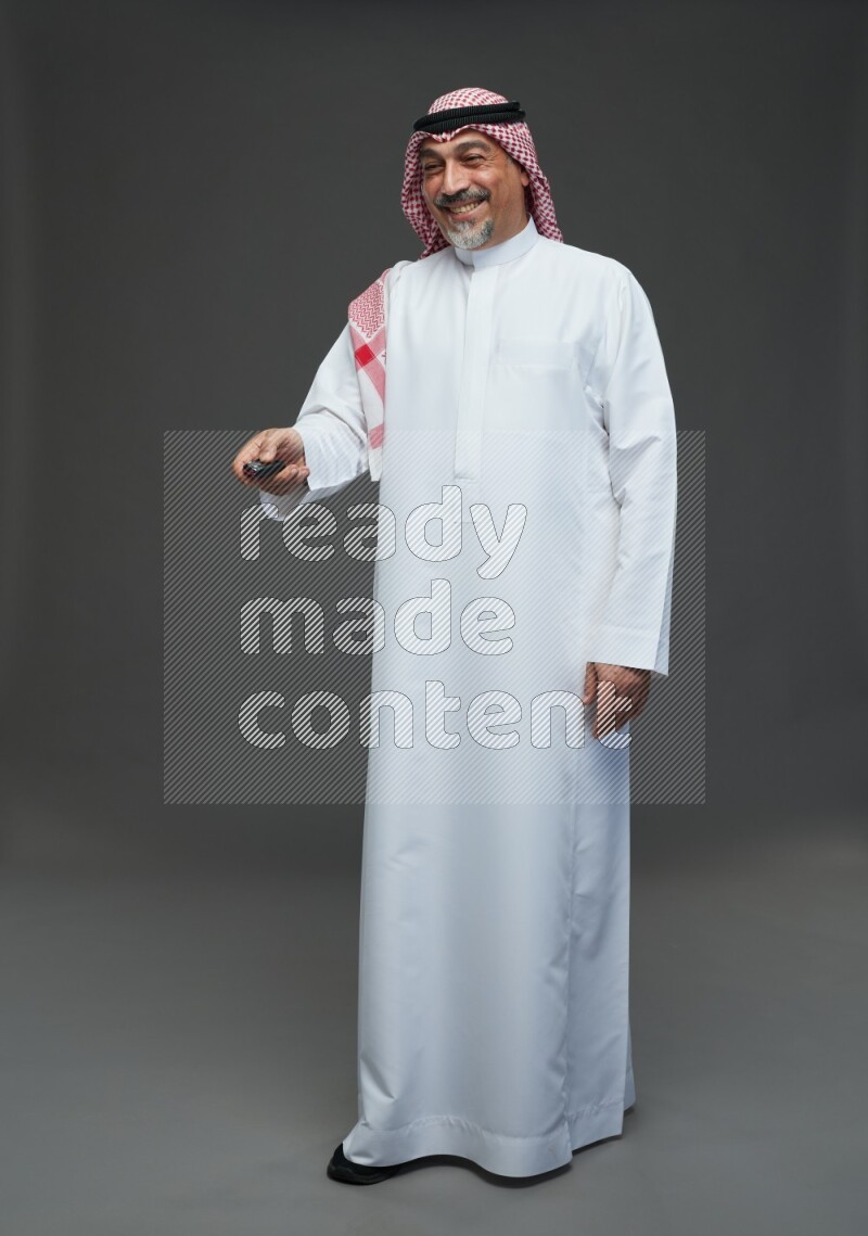 Saudi man with shomag Standing holding car key on gray background