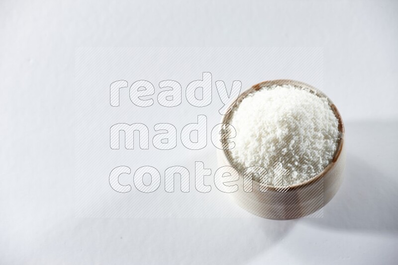A beige ceramic bowl full of desiccated coconut on a white background in different angles