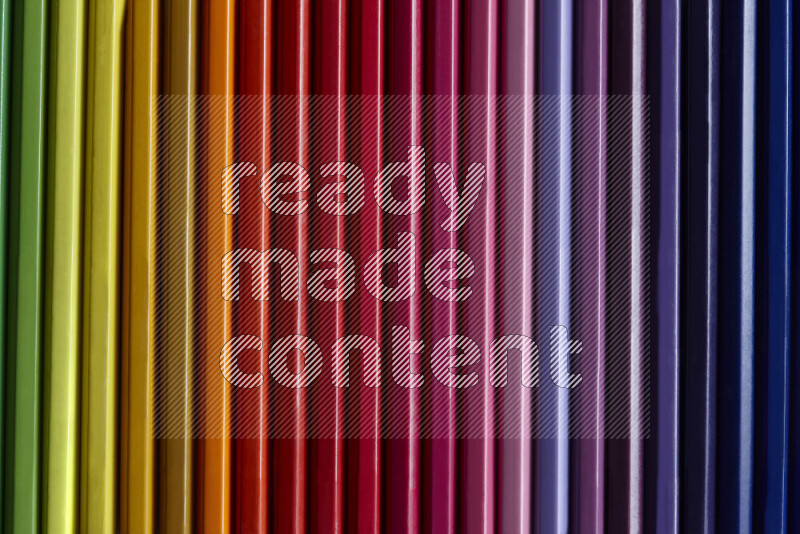 مجموعة من أقلام الرصاص الملونة مرتبة لتعرض تدرجا من الألوان المختلفة علي خلفية رمادية