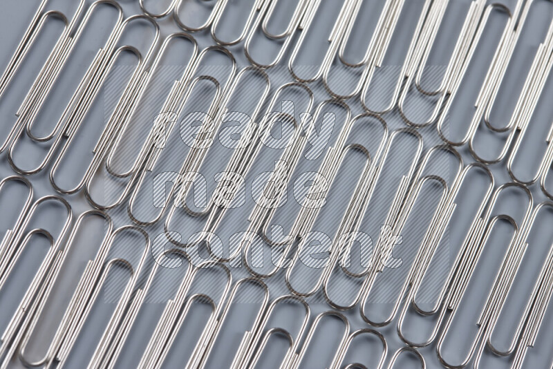 Silver paper clips isolated on a grey background