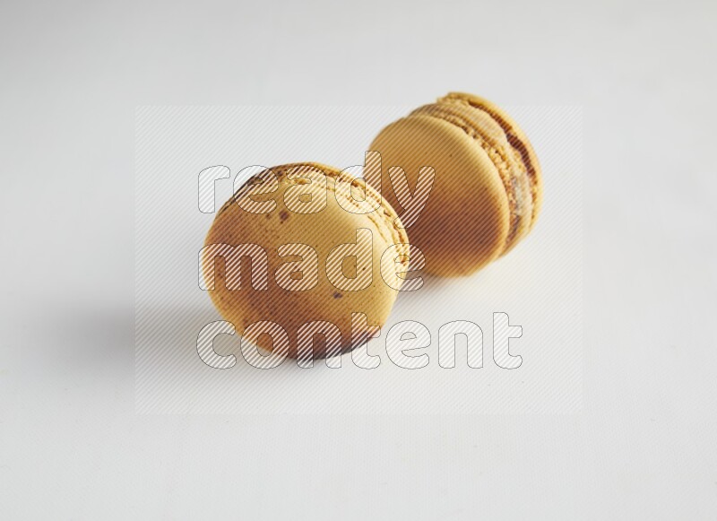 45º Shot of two Yellow Crème Brulée macarons on white background