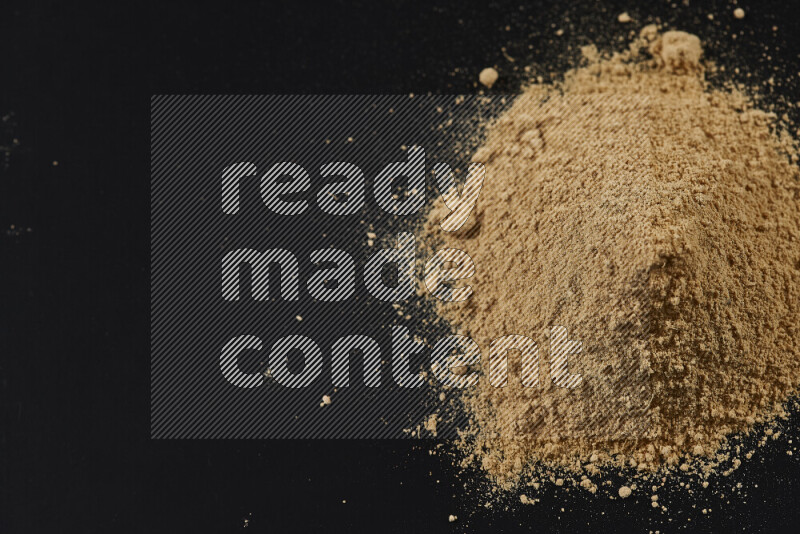 A bunch of ground ginger powder on black background