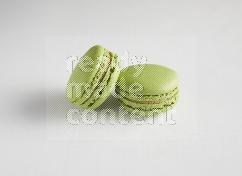 45º Shot of two Green Pistachio macarons on white background