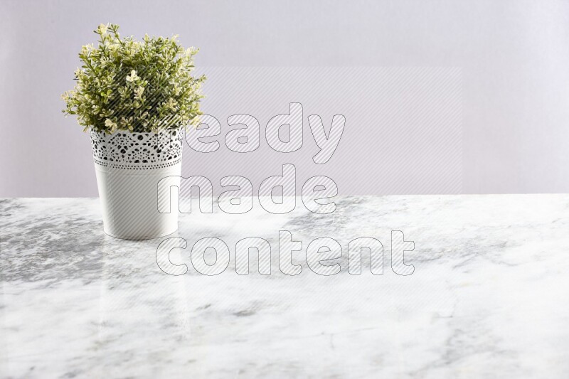 Artificial plant in white decorative pot on grey marble background