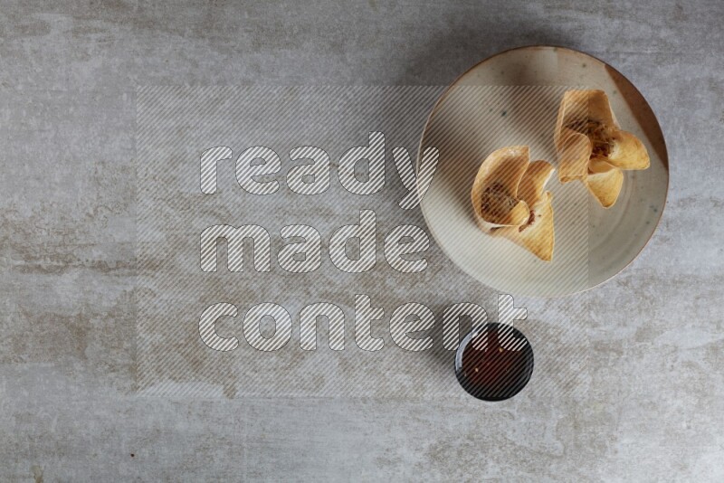 wonton cups with soy sauce ramkin on multi colored pottery on grey textured counter top