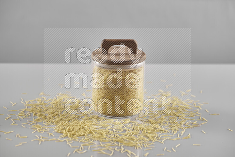 Raw pasta in a glass jar on light grey background