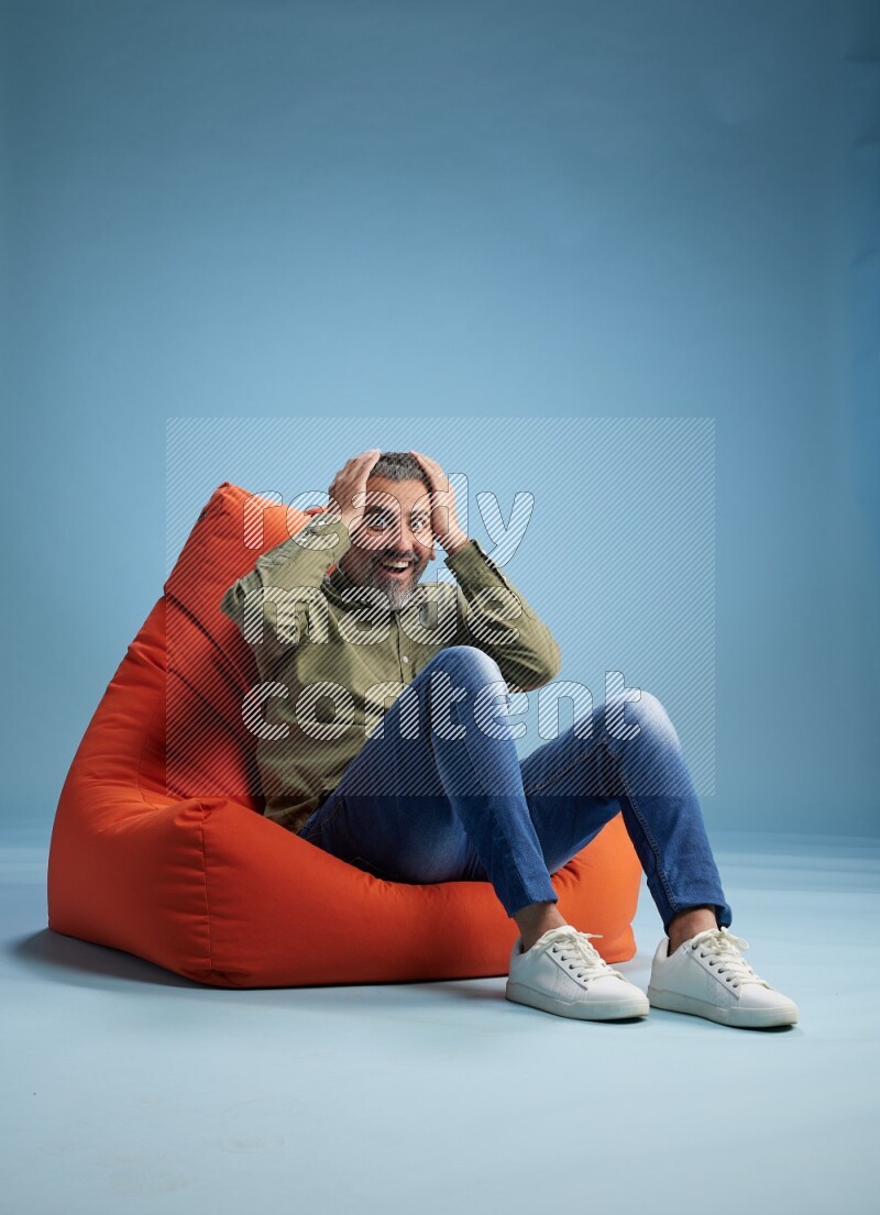 A man sitting on an orange beanbag and interacting with the camera