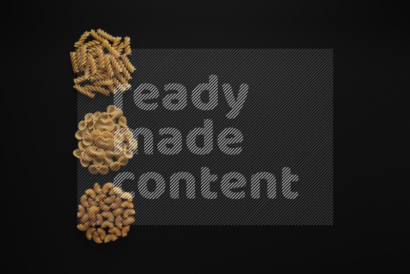 Different pasta types in 3 bunches on black background