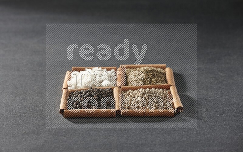 4 squares of cinnamon sticks full of black pepper, cumin, white pepper and white salt on black flooring
