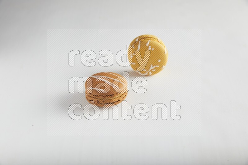 45º Shot of of two assorted Brown Irish Cream, and Yellow Piña Colada macarons on white background