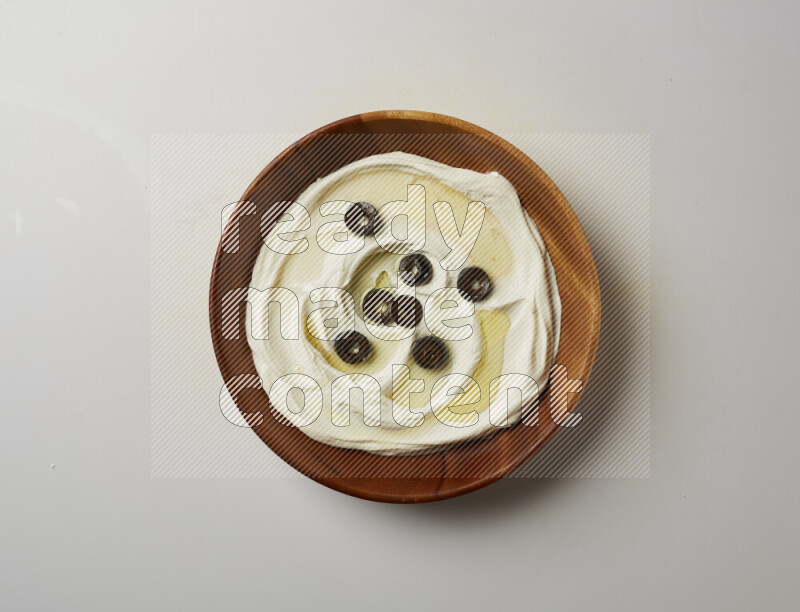 Lebnah garnished with sliced olives in a wooden plate on a white background