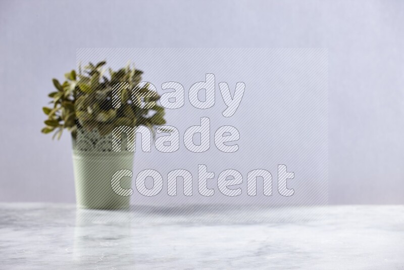Artificial plant in green decorative pot on grey marble background