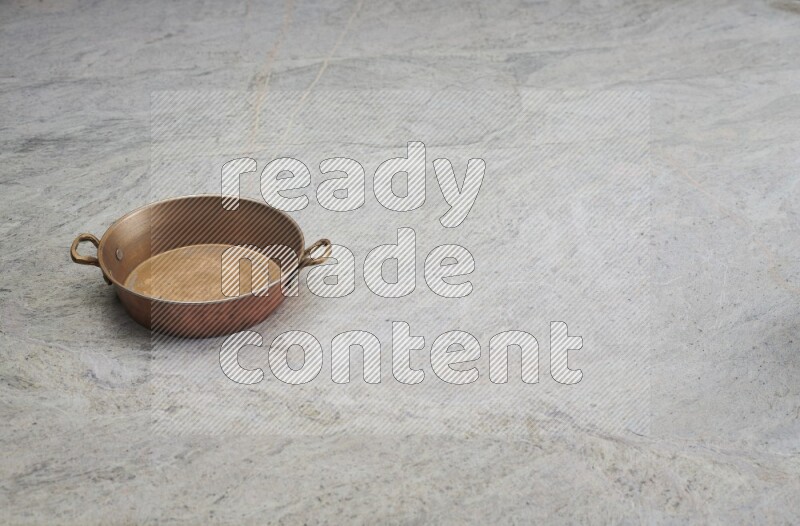 A small copper pan on grey marble background