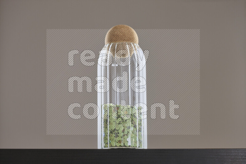 Sequins in a glass jar on black background