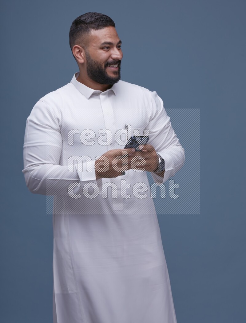 A man Texting on Blue Background wearing Saudi Thob