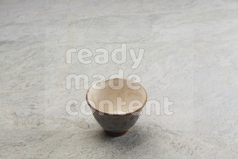 A multicolored pottery bowl on grey marble background
