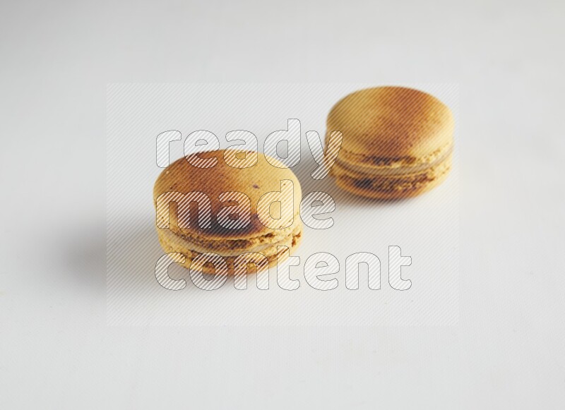 45º Shot of two Yellow Crème Brulée macarons on white background