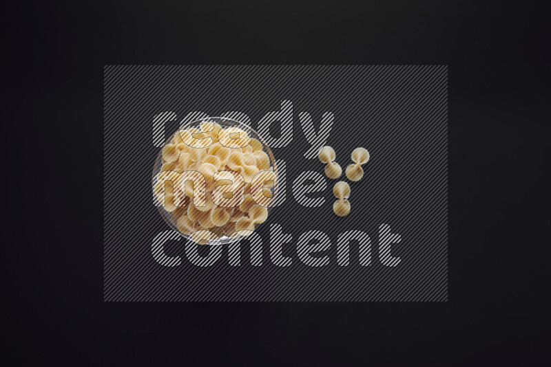 Fiocchi pasta in a glass bowl on black background