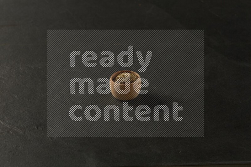 wooden round sauce bowl filled with herbs on grey textured countertop