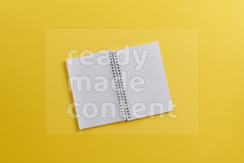 An open notebook with different school supplies on yellow background