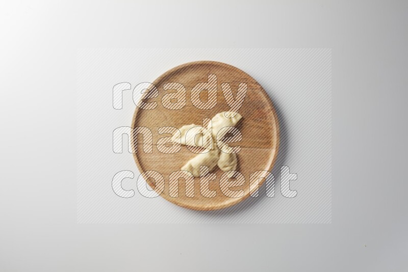 Four Sambosas on a wooden round plate on a white background