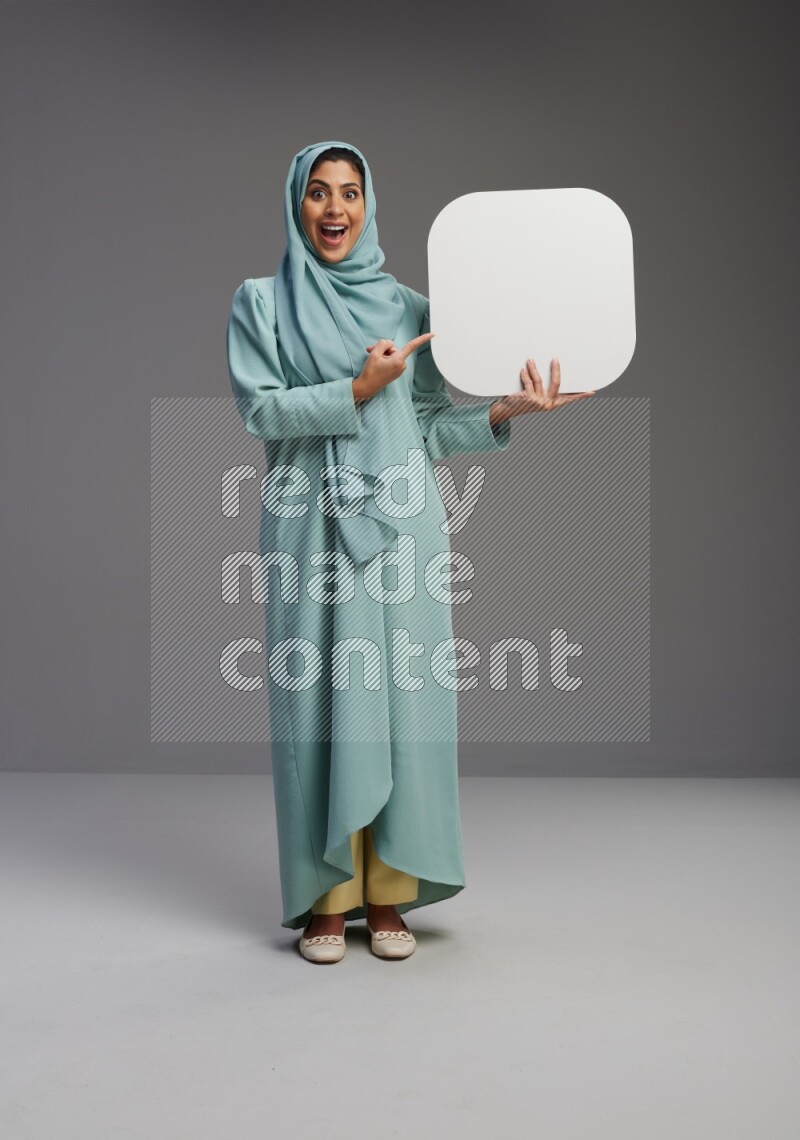 Saudi Woman wearing Abaya standing holding social media sign on Gray background