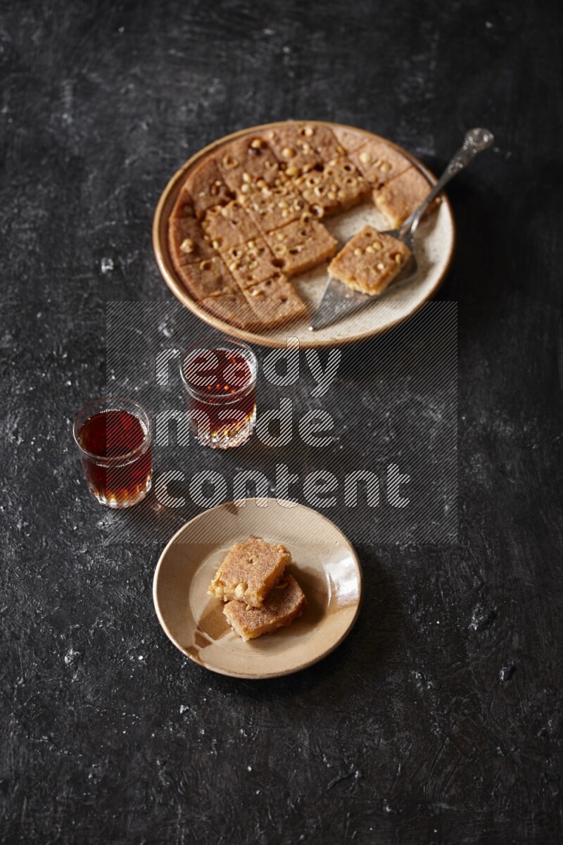 Basbousa with tea in a dark setup