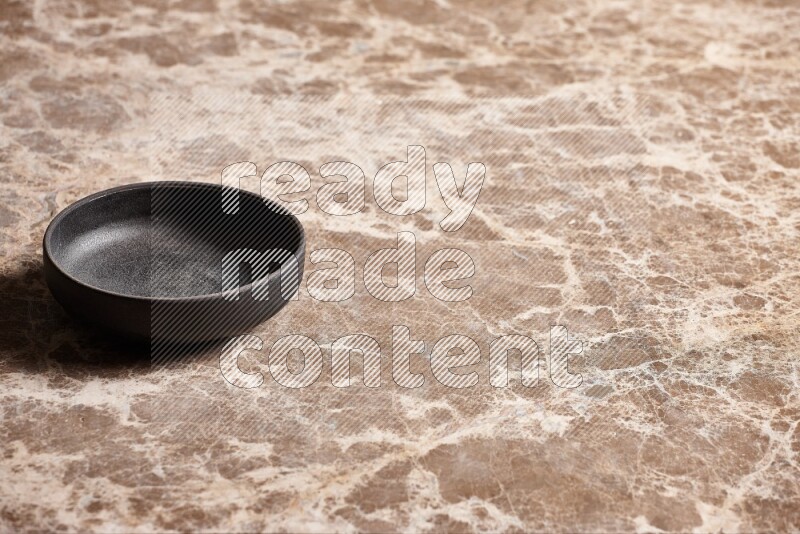 A black pottery bowl on beige marble background