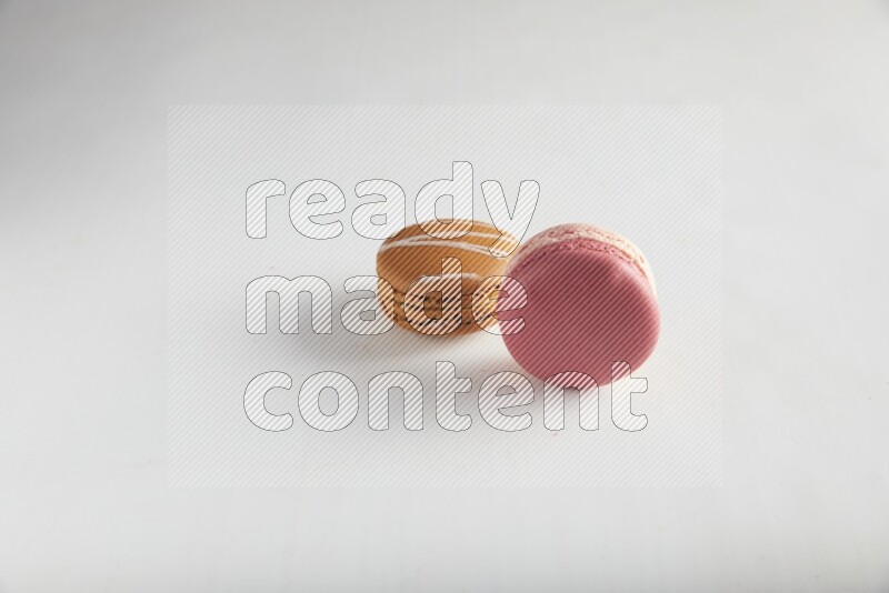 45º Shot of of two assorted Brown Irish Cream, and Pink Litchi Raspberry macarons on white background