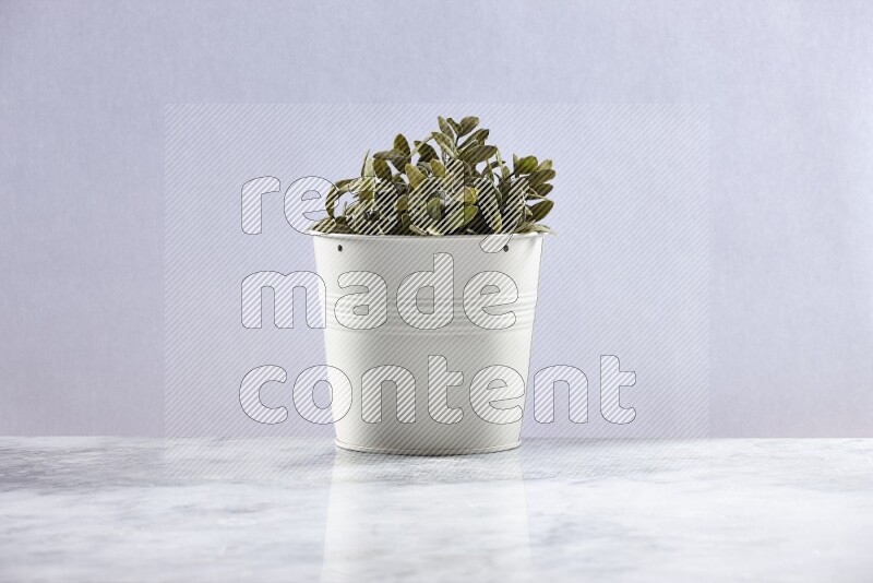 Green artificial plant in white pot on grey marble background
