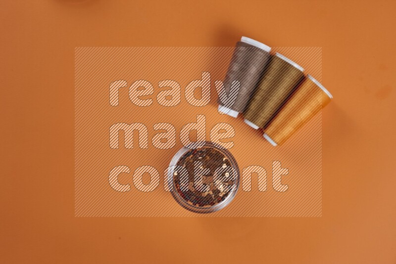 A brown collection of sewing and tailoring tools arranged on a orange background