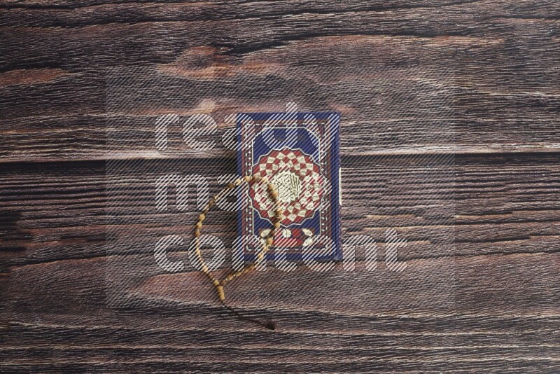Quran with a prayer beads on wooden background
