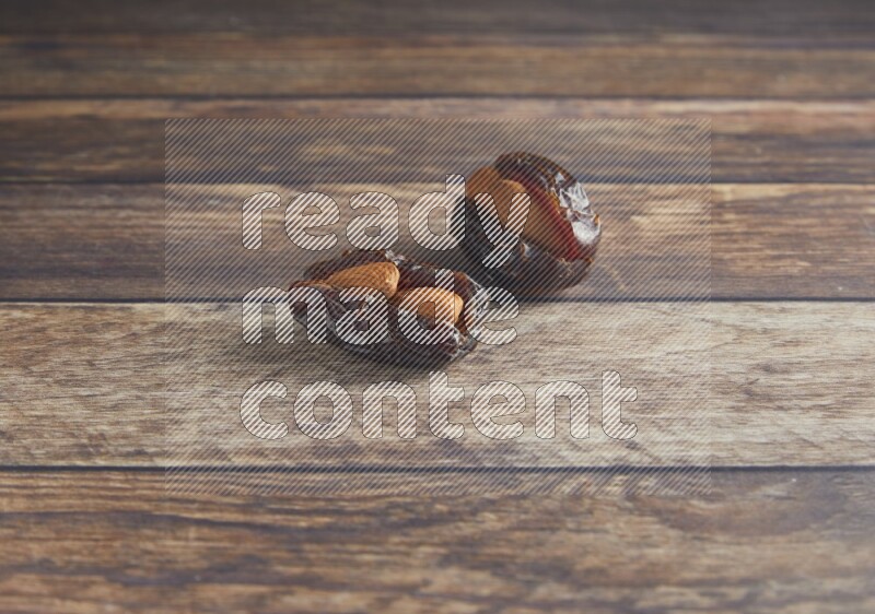 two almond stuffed madjoul dates on a wooden background