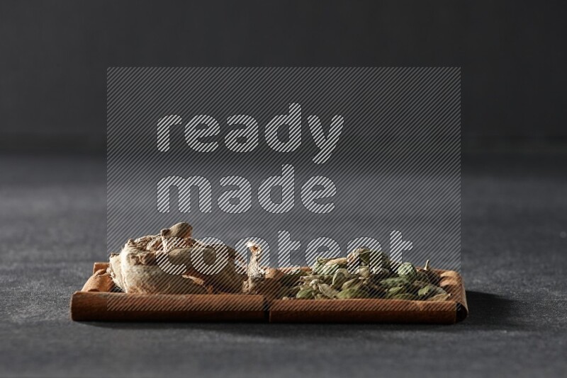 2 squares of cinnamon sticks full of cardamom and dried ginger on black flooring