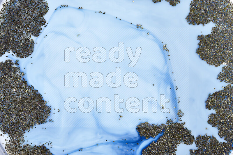 A close-up of sparkling gold glitter scattered on swirling blue background