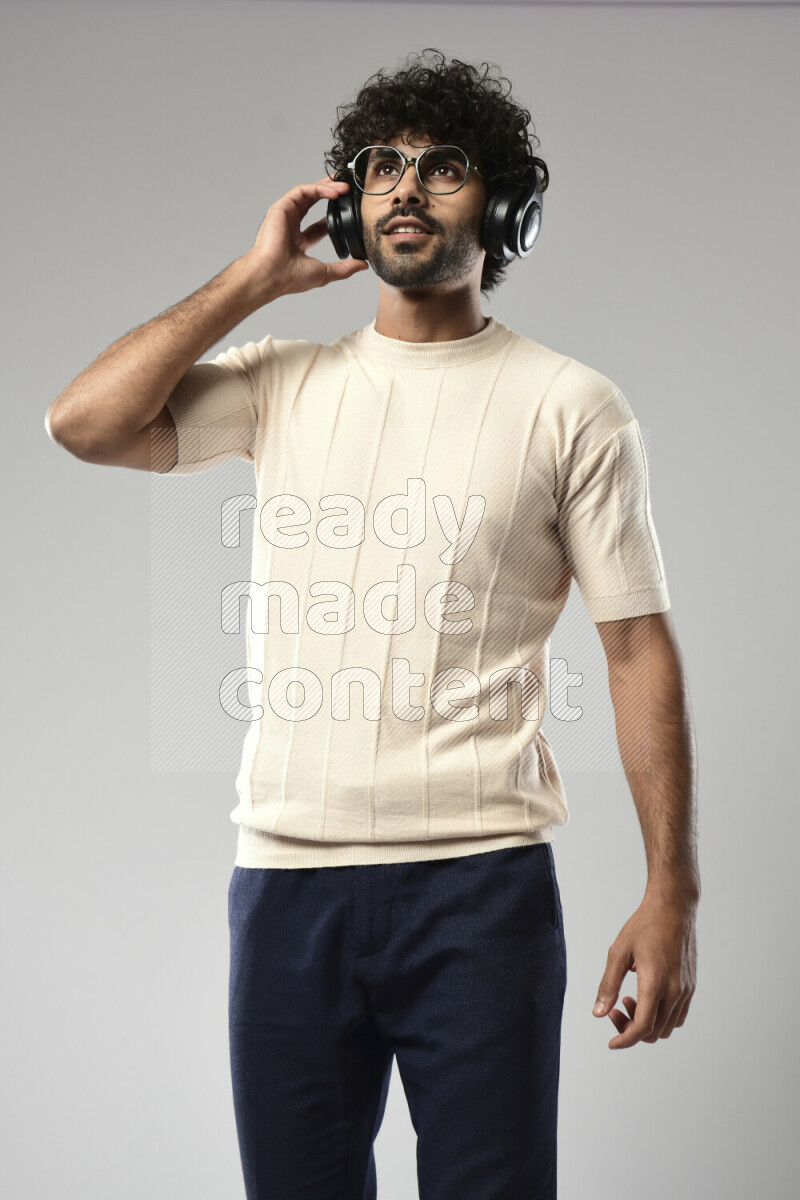 A man wearing casual standing and putting on headphones on white background