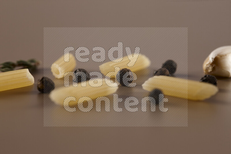 معكرونة مع مكونات متنوعة من الطماطم والثوم والبصل والفلفل الأحمر والفلفل الأسود والفلفل الأبيض وأوراق الغار وإكليل الجبل والهيل على خلفية بيج