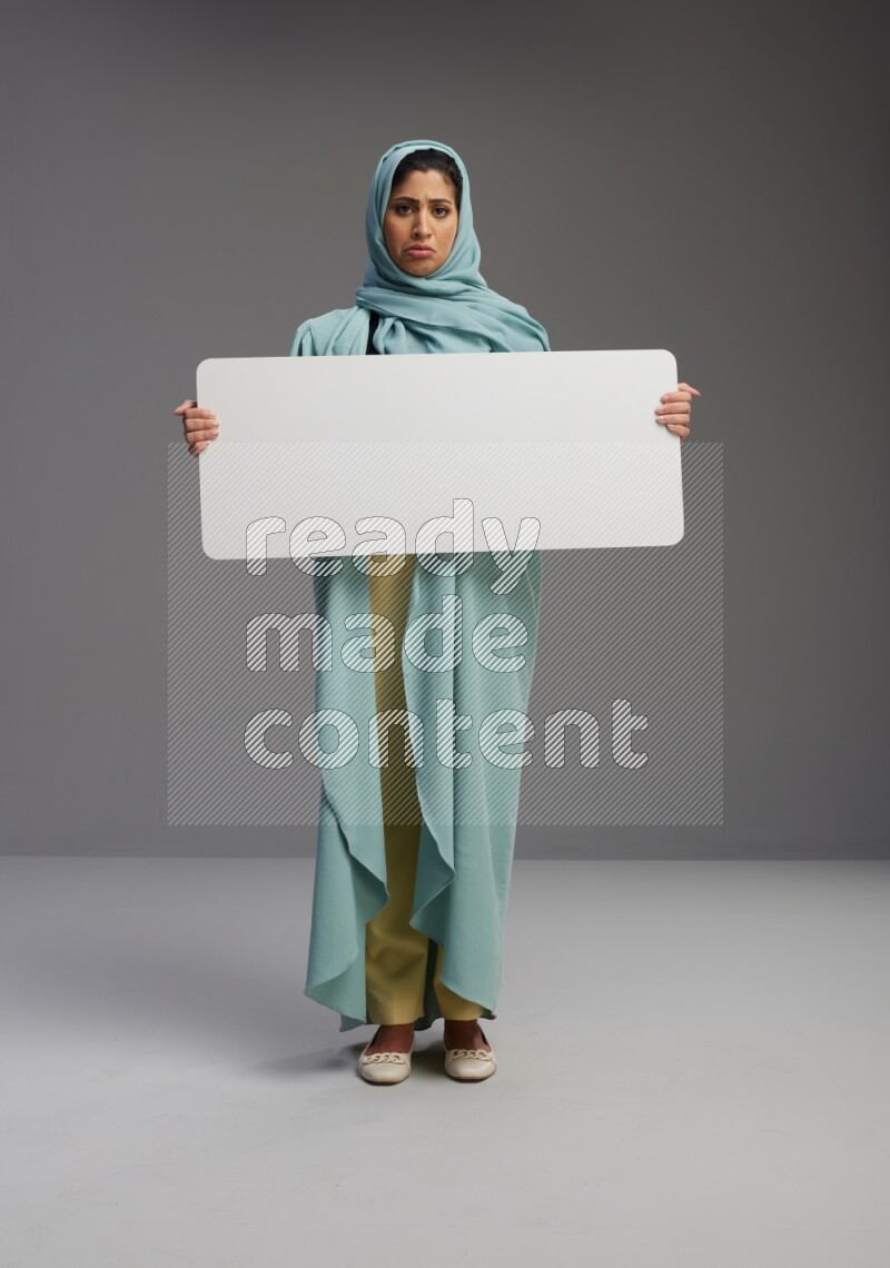 Saudi Woman wearing Abaya standing holding board on Gray background