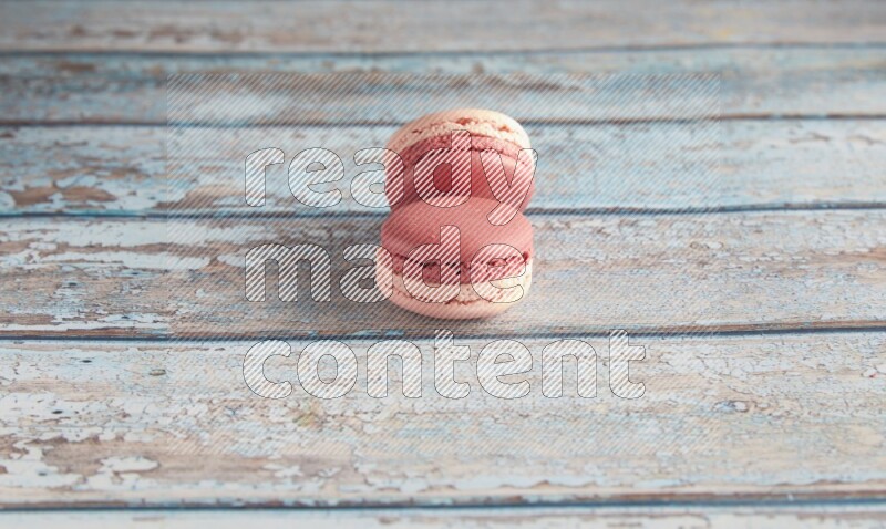 45º Shot of two Pink Litchi Raspberry macarons on light blue wooden background