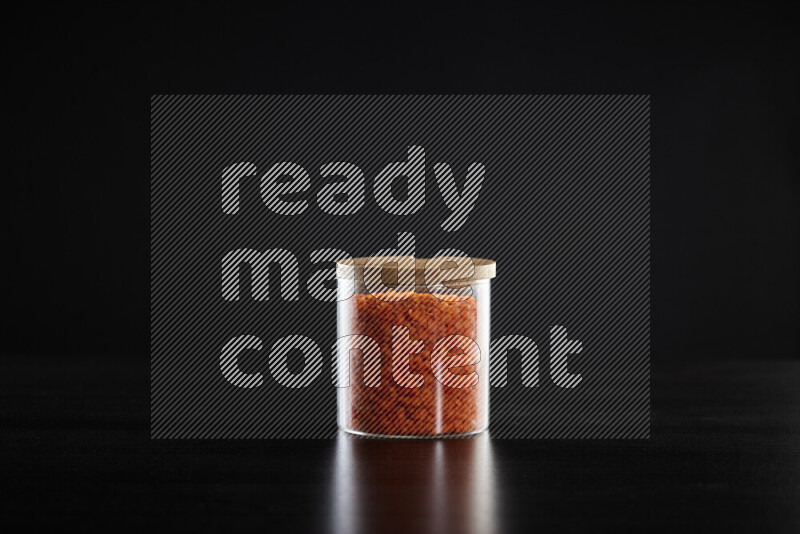 Lentils in a glass jar on black background
