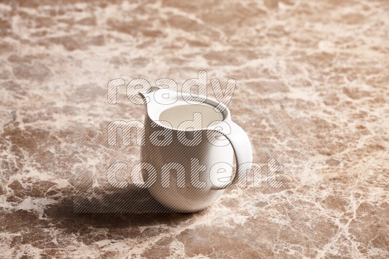 A ceramic milk jug on beige marble background