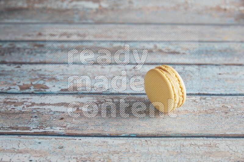45º Shot of Yellow Vanilla macaron on light blue wooden background