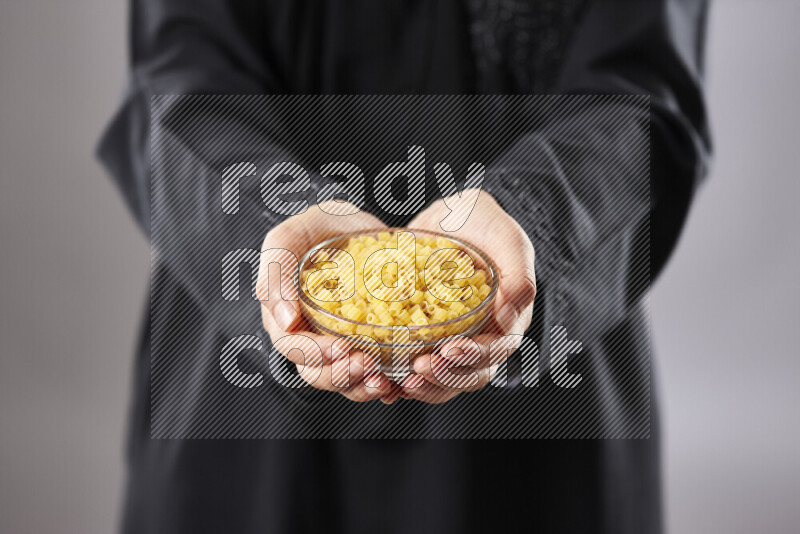 Woman in abaya holding different kinds of pasta in different positions